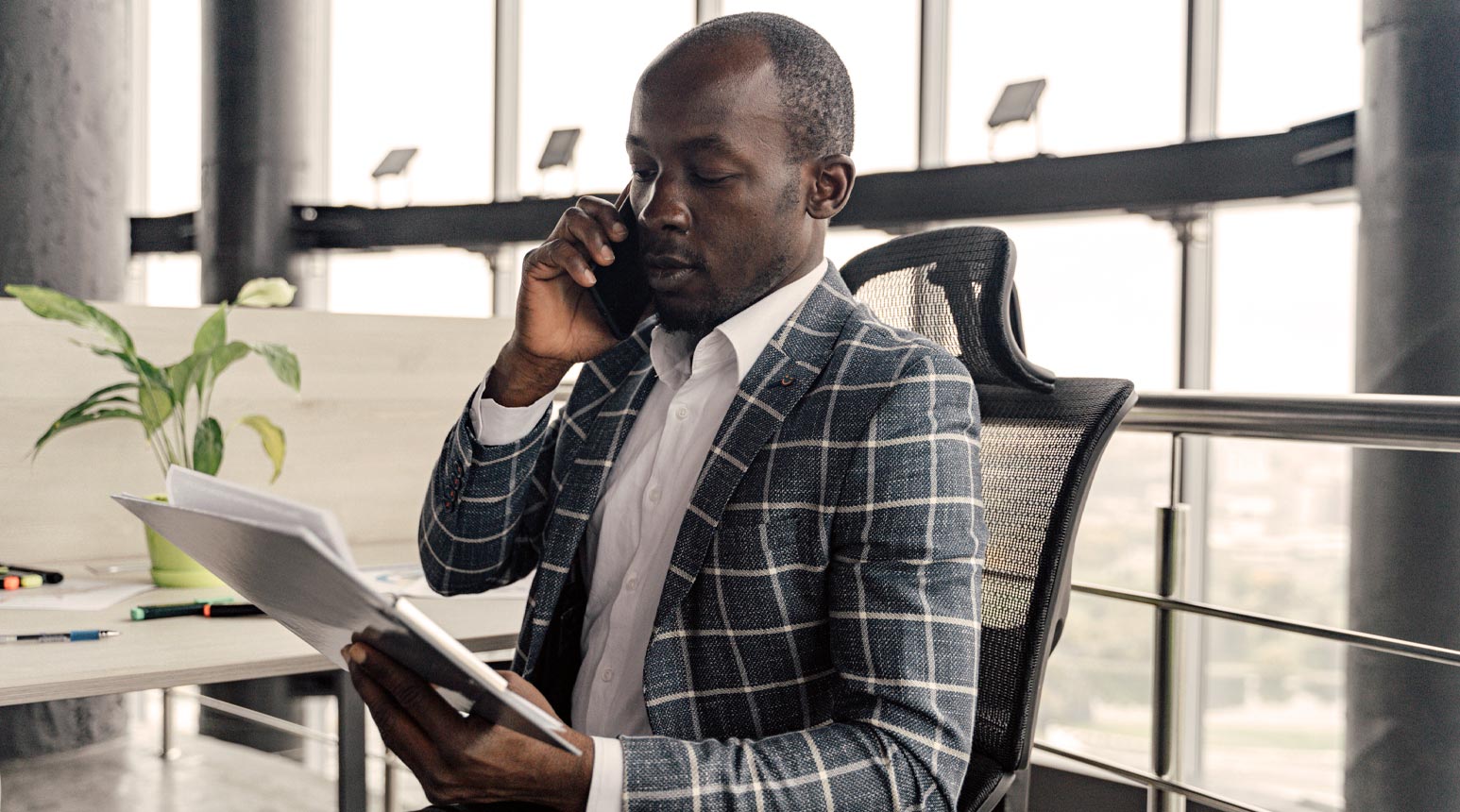 A businessman in a suit going over documents on the phone.